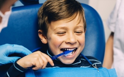 Young boy practice tooth brushing during children's dentistry visit