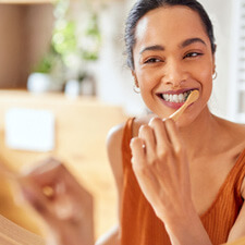 Woman smiling while brushing her teeth