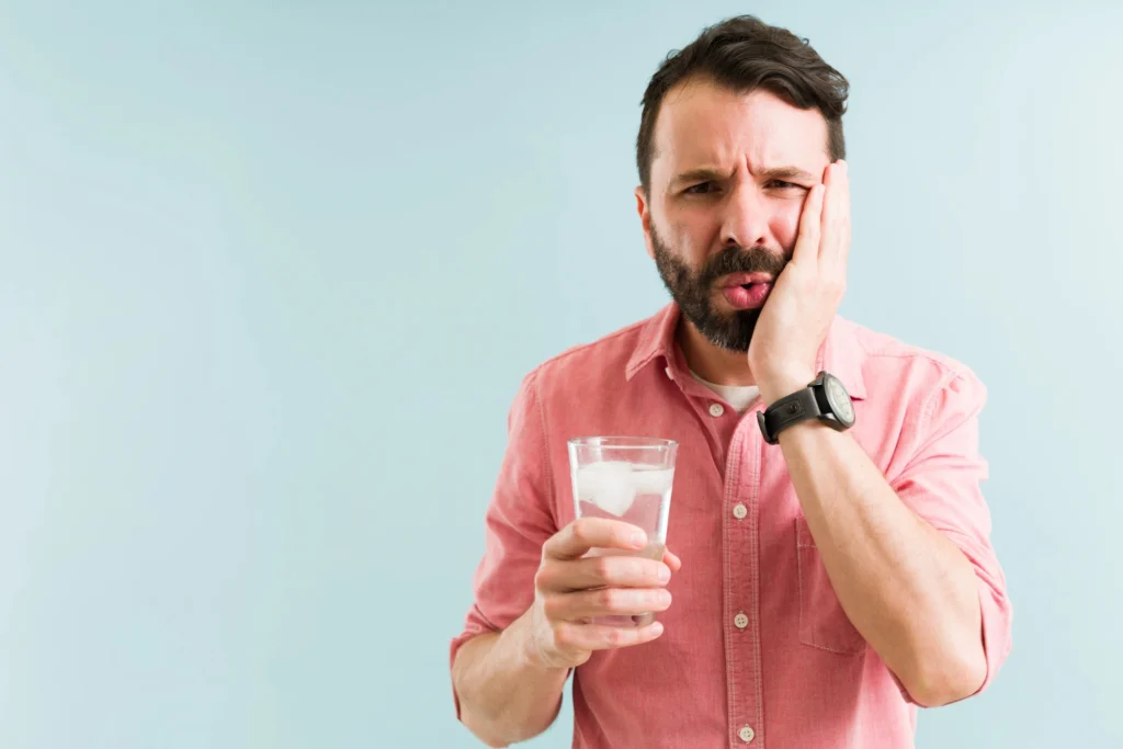 man holding glass of cold water holding his face in pain dentist Short Pump VA