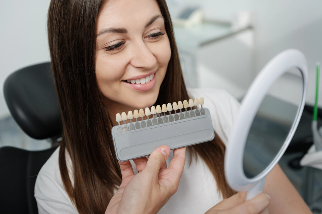 patient-smiling-while-looking-at-veneers-cosmetic-dentists-Richmond-VA