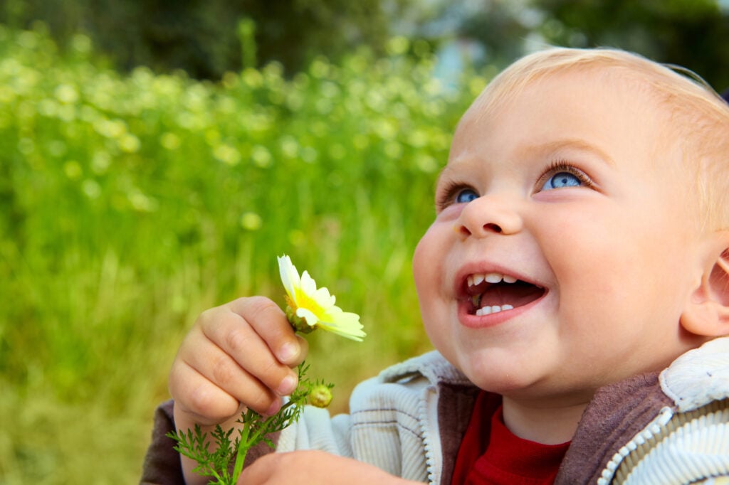 smiling baby with a flower in hand after family dentistry in Short Pump